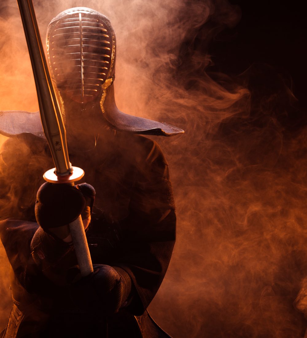 Kendo fighter in armor holding bamboo sword in smoke